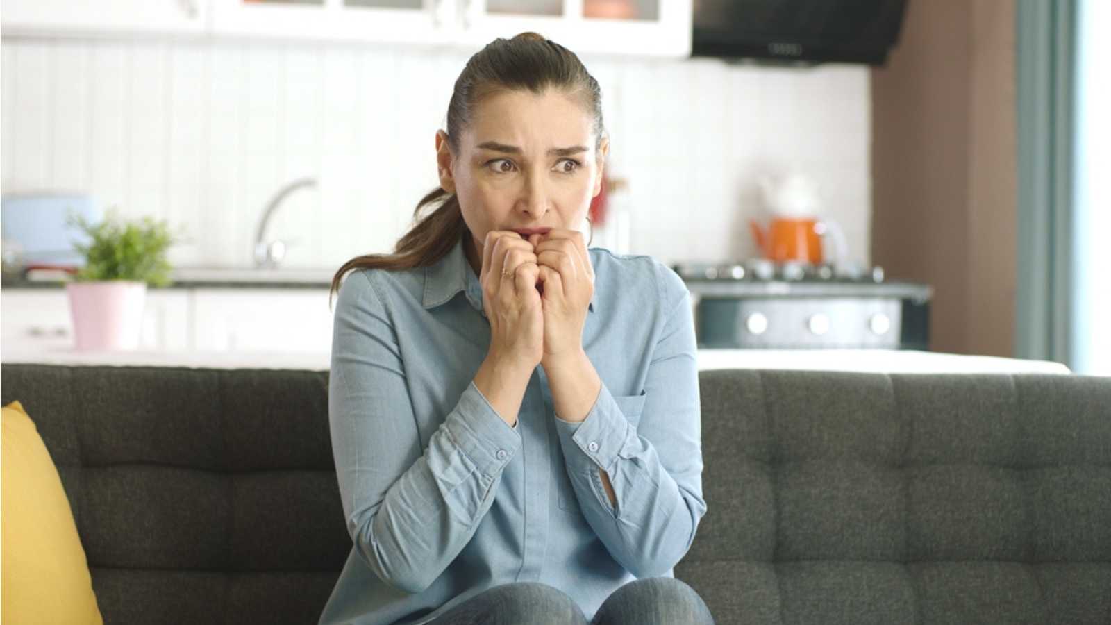 Scared Woman in sofa biting nails.