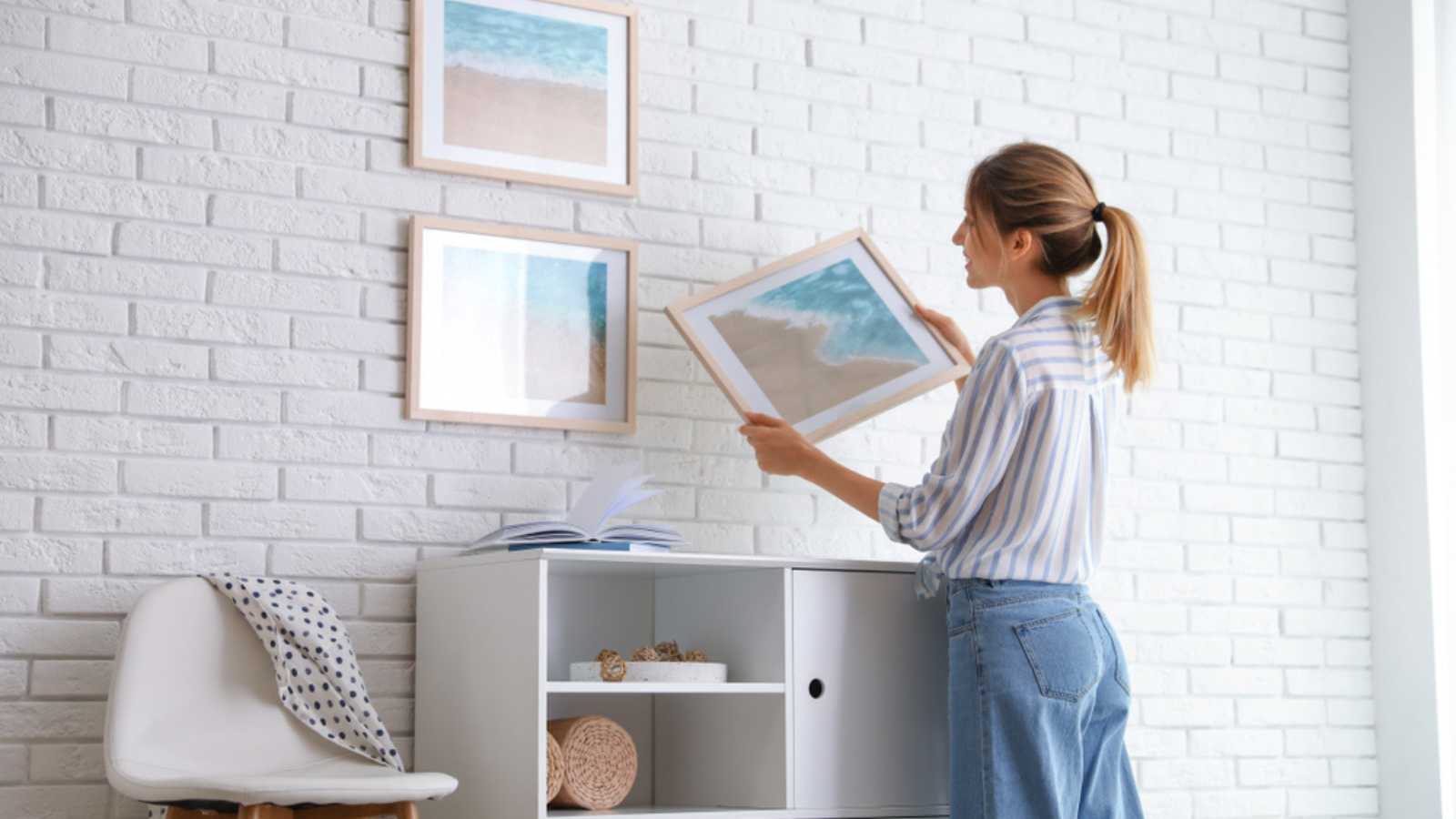 Woman hanging art on wall